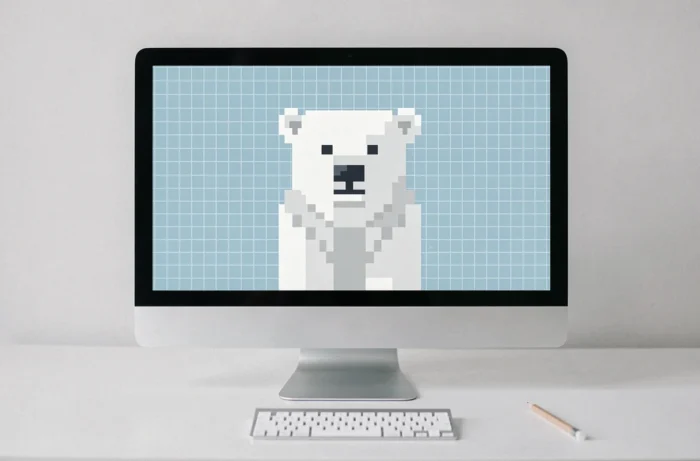 Moniteur sur bureau blanc affichant un pixel art minimaliste d'ours polaire en blanc et gris sur fond bleu glacé